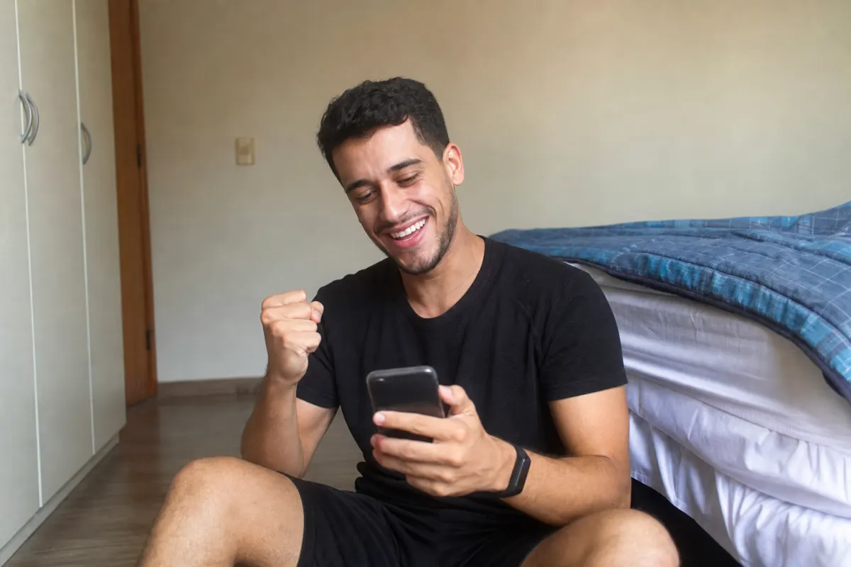 Foto ilustrativa: rapaz comemorando os likes do vídeo no celular
