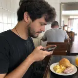 Rapaz fotografando o café da manhã na padaria