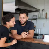 Dono de hamburgueria mostrando o celular para uma amiga