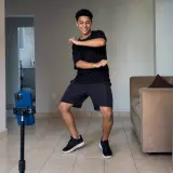 Rapaz dançando na sala com o celular no tripé