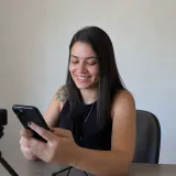 Criadora lendo mensagens no celular na escrivaninha
