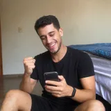 Rapaz comemorando com o celular na mão